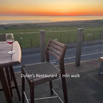 a glass of wine sitting on a table next to a road at Gwyneska in Llanaber