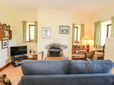 a living room with a blue couch and a fireplace at Cae'n Y Coed Barn in Talsarnau