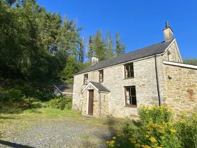 an old stone house in the middle of a field at Cae'n Y Coed Cottage in Talsarnau