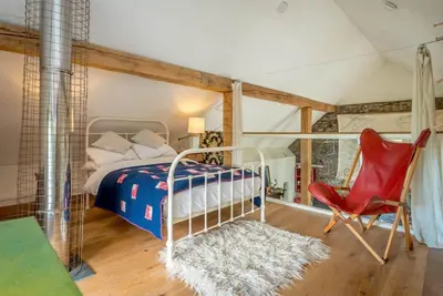 a bedroom with a bed and a red chair at Beudy-Mach in Cemmaes Road