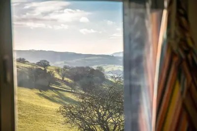 a view from a window of a field with trees at Beudy-Mach in Cemmaes Road