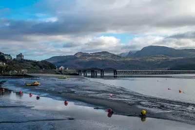 a body of water with a bridge and mountains at Beudy-Mach in Cemmaes Road