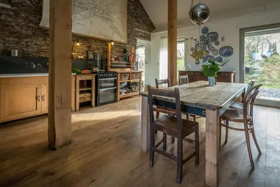 a large kitchen with a wooden table and chairs at Beudy-Mach in Cemmaes Road