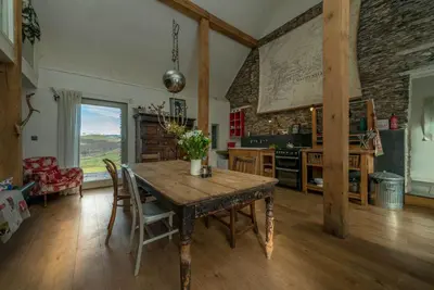 a kitchen with a wooden table in a room at Beudy-Mach in Cemmaes Road
