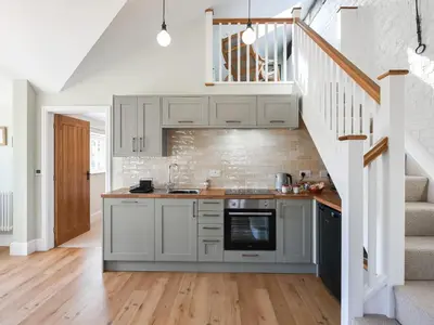 a kitchen with white cabinets and a staircase at The Vinery - Uk49583 in Shrewsbury
