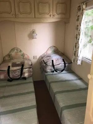two beds in a small room with a window at Northfield Holiday Park in Borth