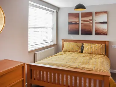 a bedroom with a bed and a desk and a window at Cae Cwta in Llanddwywe