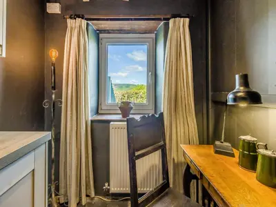 a kitchen with a window with a radiator and a table at 3 Legged Duck Cottage in Yspytty-Ystwyth
