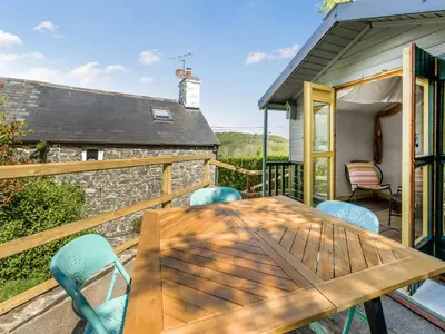 a wooden table and chairs on the deck of a cottage at 3 Legged Duck Cottage in Yspytty-Ystwyth