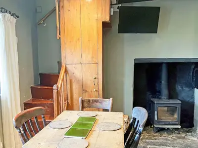 a dining room with a table and a wood stove at 3 Legged Duck Cottage in Yspytty-Ystwyth