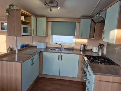 a kitchen with white cabinets and a sink at Caravan in Picturesque New Quay Wales in New Quay