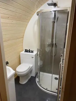 a bathroom with a toilet and a glass shower at Mynd View Pods Ash in Craven Arms