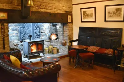 a living room with a stone fireplace and a couch and a table at Lion Royal Hotel, Rhayader in Rhayader