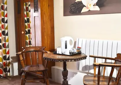 a table with a kettle on it next to two chairs at Lion Royal Hotel, Rhayader in Rhayader