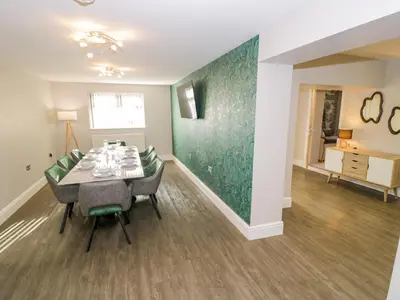a dining room with a table and green wall at Bwthyn Y Mor in Llanddwywe