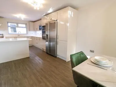 a kitchen with a stainless steel refrigerator and a table at Bwthyn Y Mor in Llanddwywe