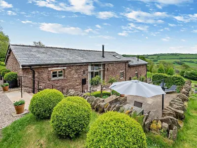 a brick house with an umbrella in front of it at 2 Bed in Hereford oc-42881 in Craswall
