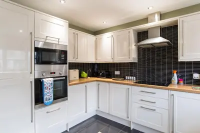 a white kitchen with white cabinets and appliances at Maes Bach Boutique GUEST HOUSE TOWN CENTRE in Aberystwyth