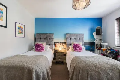 two beds in a room with purple pillows at Maes Bach Boutique GUEST HOUSE TOWN CENTRE in Aberystwyth