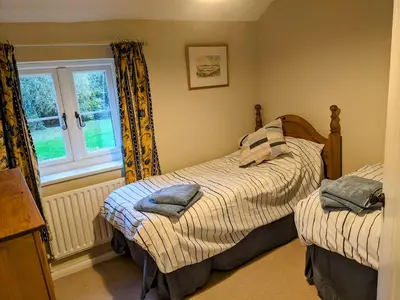 a bedroom with two beds and a window at The Byre in Yeaton