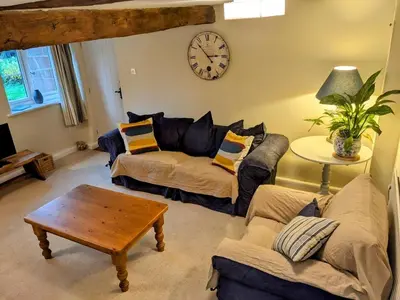 a living room with a couch and a clock on the wall at The Byre in Yeaton