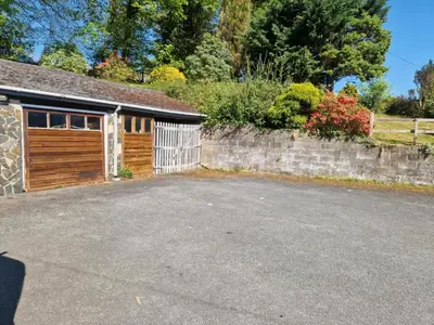 a house with a garage and a stone wall at Y Fedw Wen in Bont Newydd