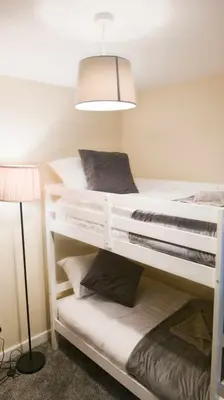 two bunk beds in a room with a lamp at Y Fedw Wen in Bont Newydd