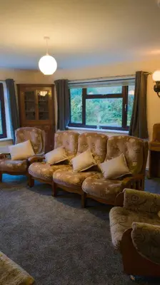 a living room with a leather couch and a window at Y Fedw Wen in Bont Newydd