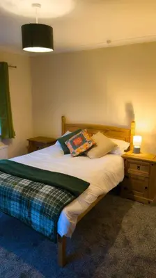 a bedroom with a wooden bed with a nightstand and a bed sidx sidx sidx at Y Fedw Wen in Bont Newydd