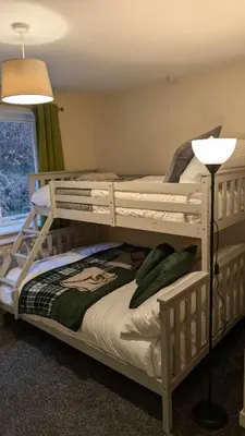 two bunk beds in a room with a lamp at Y Fedw Wen in Bont Newydd