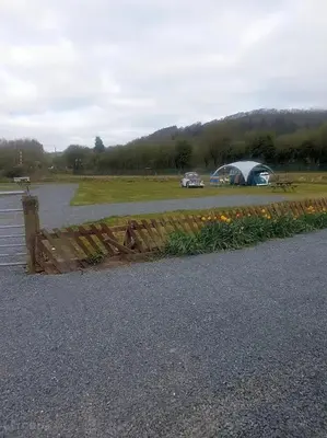 a fence and a tent and a field with flowers at Green Dragon and Kitchen Pod - Sleeps 2 & Parking in Welshpool