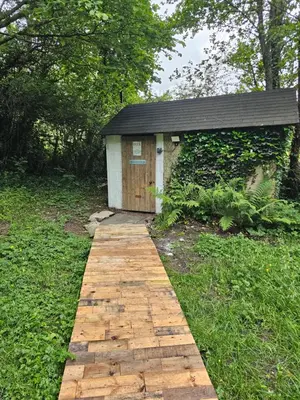 a wooden path leading to a small building at Bluebell Hideaway in Llanfair Clydogau