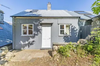 a small grey shed with a white door at 1 Bed in Llwyngwril oc-a31970 in Llwyngwril