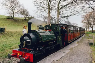 a train traveling down the tracks with two people on it at 1 Bed in Llwyngwril oc-a31970 in Llwyngwril