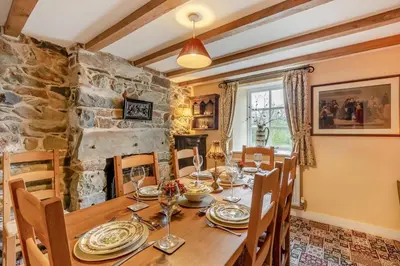 a dining room with a wooden table and a stone wall at 4 Bed in Arthog oc-b31966 in Arthog