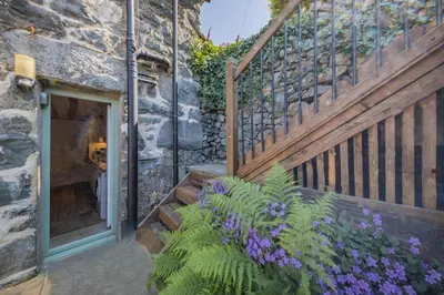 a stone building with a staircase and purple flowers at 1 Bed in Harlech oc-t32043 in Harlech