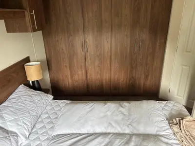 an unmade bed in a bedroom with wooden cabinets at The Bay Pearl 2 Bedroom Elegant Pet Free Stay at Clarach in Aberystwyth