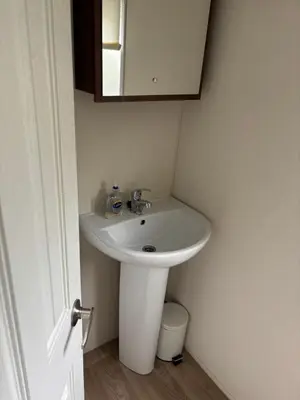 a bathroom with a white sink and a mirror at The Bay Pearl 2 Bedroom Elegant Pet Free Stay at Clarach in Aberystwyth
