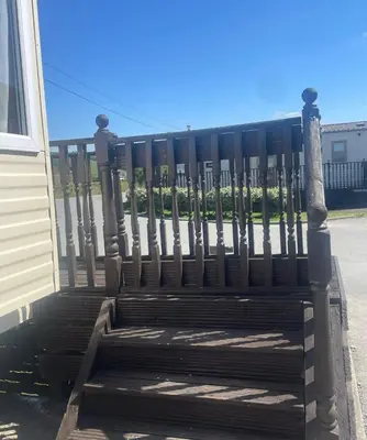 a wooden bench sitting next to a fence at The Bay Pearl 2 Bedroom Elegant Pet Free Stay at Clarach in Aberystwyth