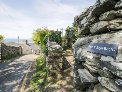 a stone wall with a sign for may y bryn beach at Pen Y Bryn Bach in Harlech