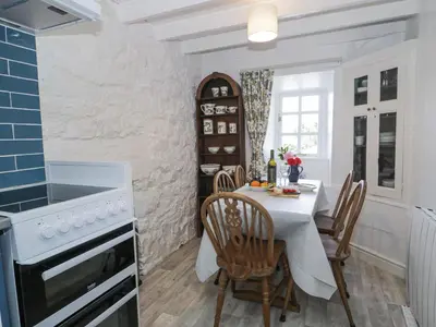 a kitchen with a white table and chairs and a stove at Pen Y Bryn Bach in Harlech