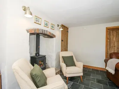 a living room with two chairs and a wood stove at Pennal Cottage in Oswestry