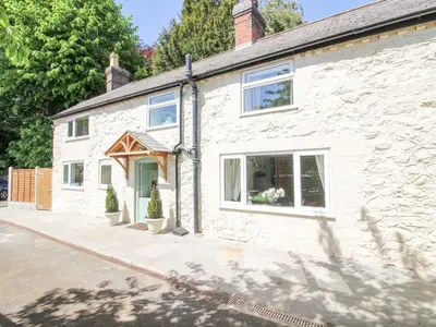 a white stone house with a window at Pennal Cottage in Oswestry