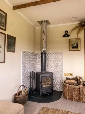 a fireplace in a living room with a stove at The Meadow Snug in Baschurch
