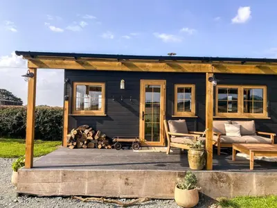 a black tiny house on a wooden deck at The Meadow Snug in Baschurch