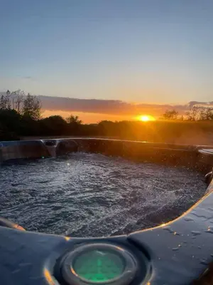 a jacuzzi tub with the sunset in the background at Cottage in Synod Inn with Hot Tub in Synod