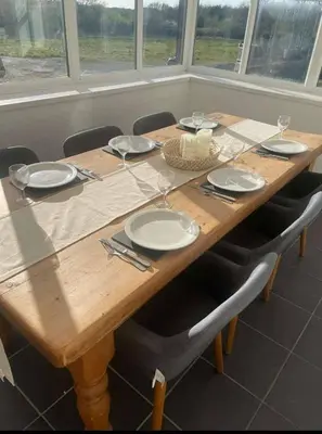 a wooden table with chairs and plates and glasses on it at Cottage in Synod Inn with Hot Tub in Synod