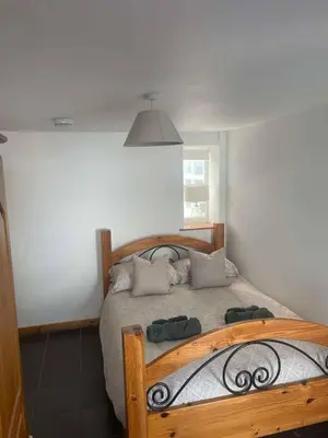 a bedroom with a wooden bed with pillows on it at Cottage in Synod Inn with Hot Tub in Synod