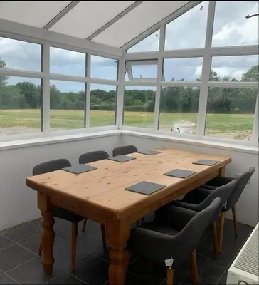a wooden table in a room with windows at Cottage in Synod Inn with Hot Tub in Synod
