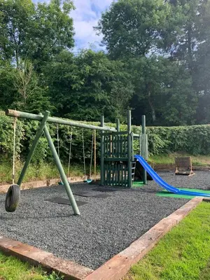 a playground with a swing set and a slide at Y Dderwen Aberaeron in Llanarth